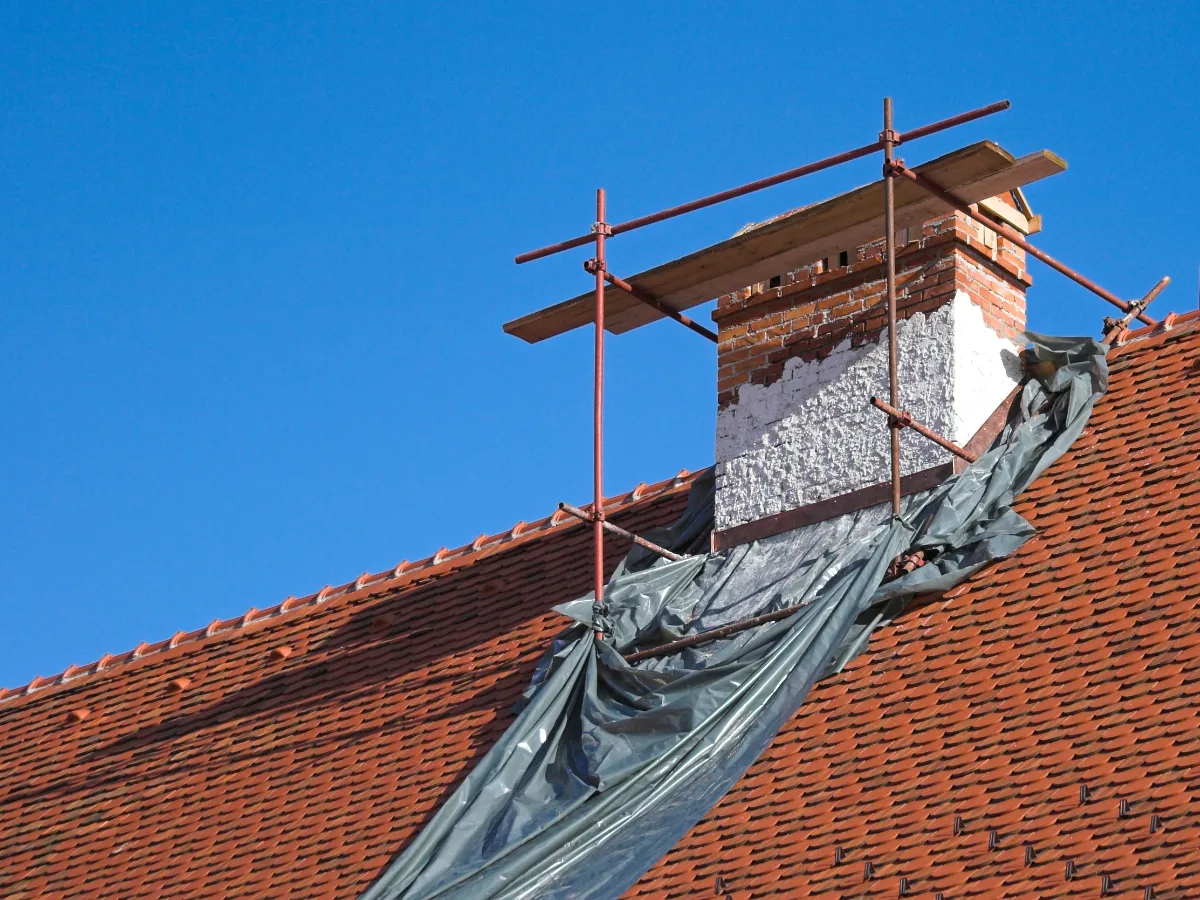 A chimney stack under works with scaffold and sheeting
